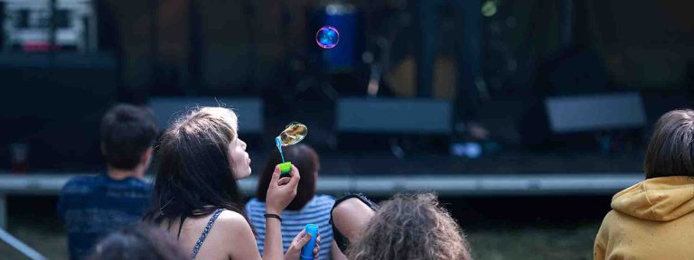 Návštěvnictvo festivalu před pódiem, dívka pouští bubliny