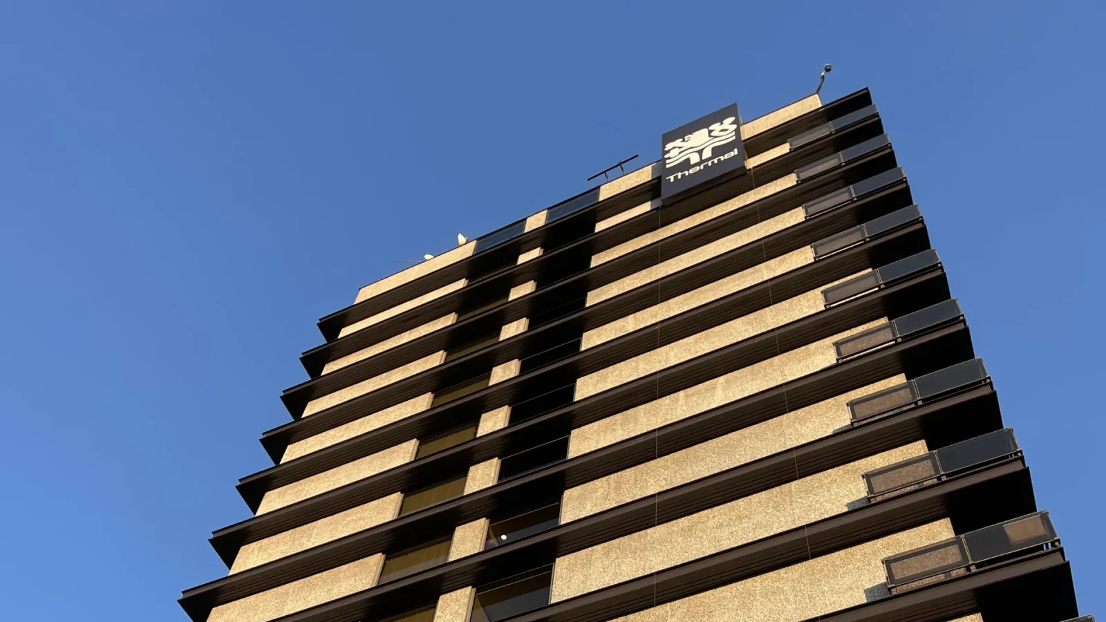 Budova hotelu Thermal zdola proti modré obloze.