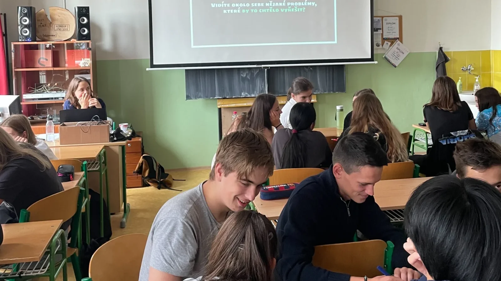 Studující ve třídě sledují promítanou otázku, zda kolem sebe vidí problémy k řešení.